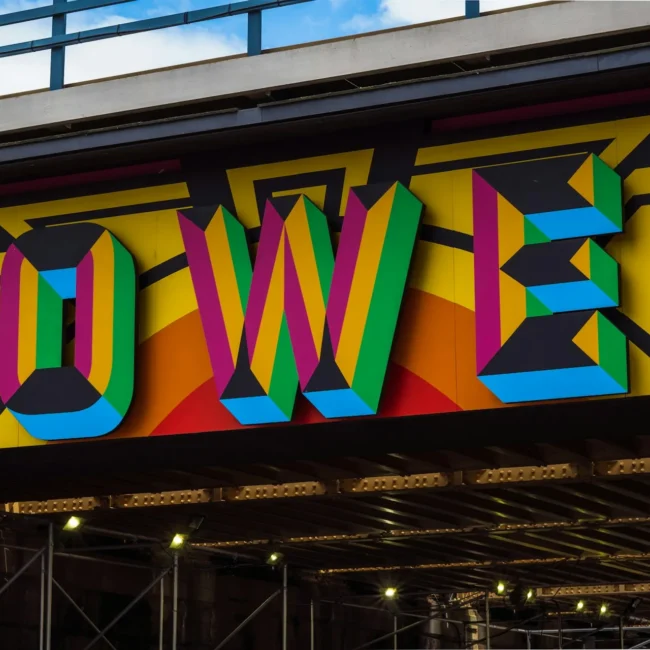 Bunte Wandgestaltung mit großem Schriftzug ‚POWER‘ in kräftigen Farben unter einer Brücke