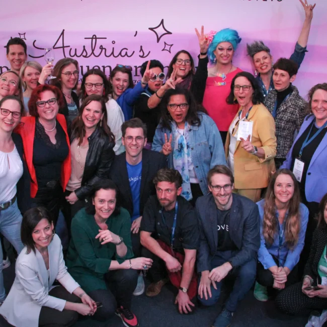 Eine Gruppe von Menschen, HR Expert*innen, jubeln vor der Leinwand Austria's Top HR Influencer*innen.