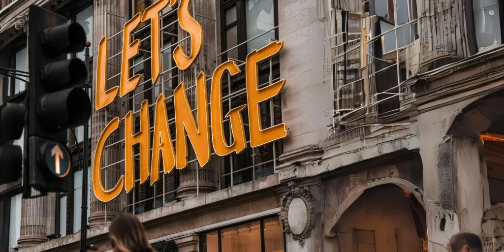 Fassade eines historischen Gebäudes mit großem Schriftzug ‚LET’S CHANGE‘ in leuchtendem Orange