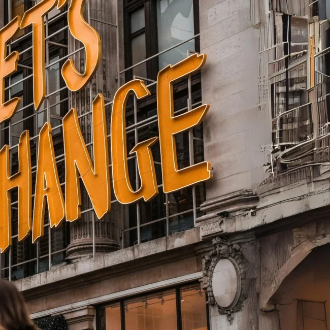 Fassade eines historischen Gebäudes mit großem Schriftzug ‚LET’S CHANGE‘ in leuchtendem Orange