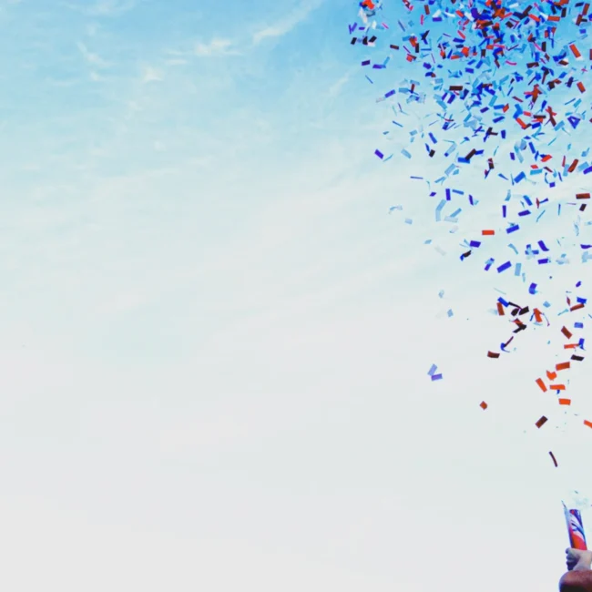 Erfolge feiern – eine junge Frau jubelt über erreichte Ziele mit einer Konfettikanone